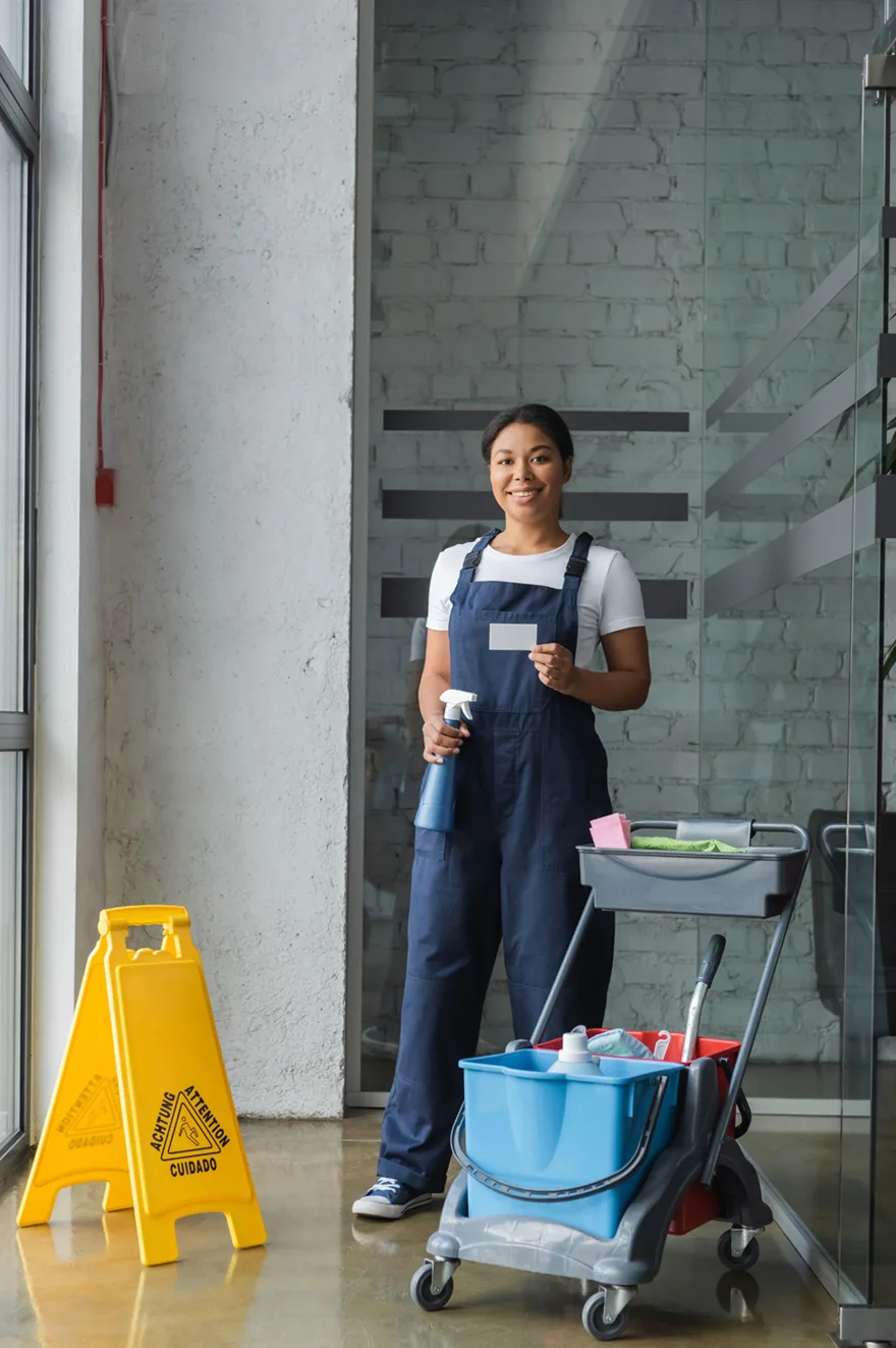 Schoonmaker met werkwagen in de gang van een kantoorgebouw